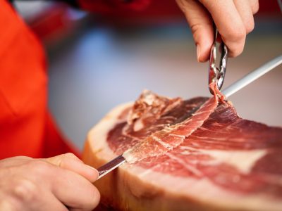 Persona cortando un jamón manuealmente